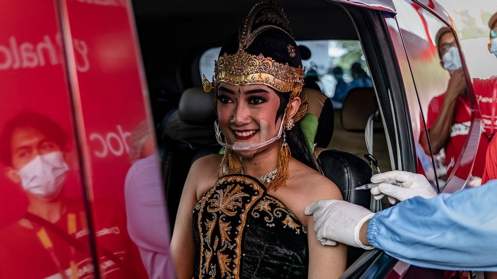 A woman wearing javanese traditonal costume in a vehicle receives a dose of the Sinovac Biotech Ltd. Covid-19 vaccinein during a mass drive-thru vaccination program at Prambanan temple complex in Yogyakarta, Indonesia. (Ulet Ifansasti/Getty Images)