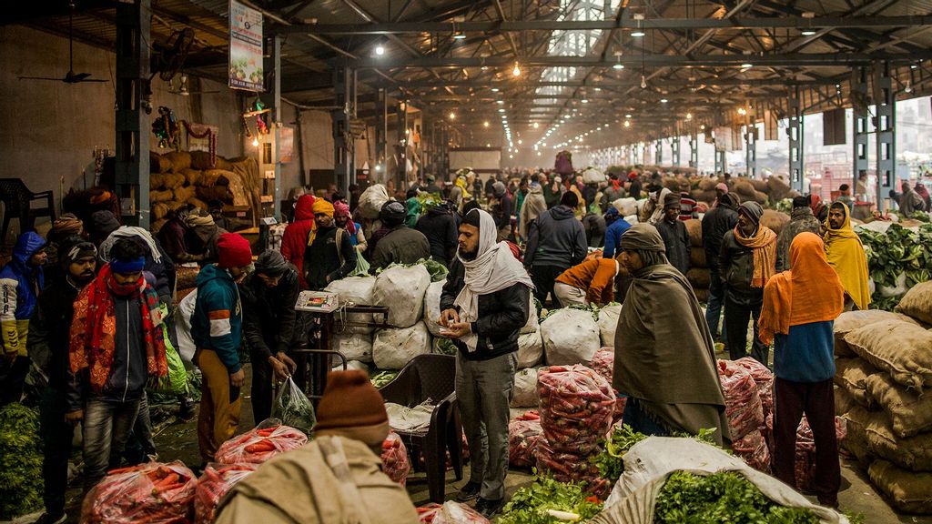 Farmers, commission agents and wholesale buyers mingle as they trade agricultural produce from Bulandshahr at the Azadpur Mandi (wholesale market) on January 17, 2021 in Azadpur, on the outskirts of Delhi, India. (Anindito Mukherjee/Getty Images)