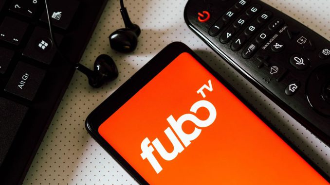 In this photo illustration, the logo of the FuboTV, an American television streaming service seen displayed on a smart phone next a Tv remote control, earphones and a keyboard. FuboTV Inc is a sports-first, live TV streaming company, offering subscribers access to tens of thousands of live sporting events annually as well as news and entertainment content. RAFAEL HENRIQUE/BENZINGA