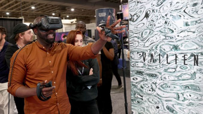 An attendee tries the virtual reality demonstration setup in the AEXLAB booth during the DCentral Miami Conference in November 2021 in Miami, Florida. Such systems are part of the fast-growing physical/digital metaverse. (Joe Raedle/Getty Images)