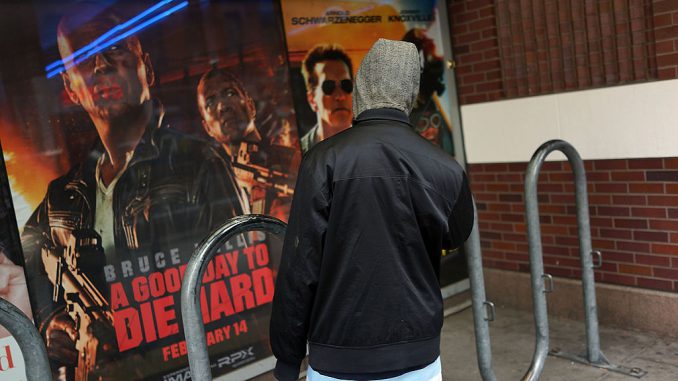 A teen stands in front of posters advertising new action films at a Brooklyn movie theater on January 11, 2013 in New York City.  (Photo by Spencer Platt/Getty Images)