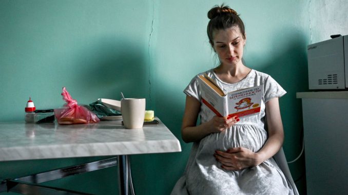 A pregnant woman reads a book in a ward at maternity hospital N9, Zaporizhzhia, southeastern Ukraine. The women are examined during the second trimester of pregnancy, when are screened for diabetes. DMYTRO SMOLIENKO/SWNS TALKER