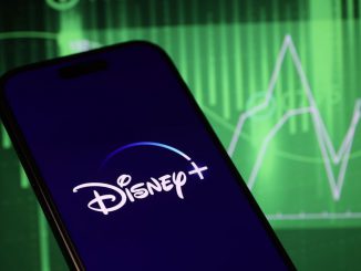 In this photo illustration, logo of Disney+ is displayed on mobile phone screen in front stock exchange screen. Disney stock receive bad ratings from McQuarie Research with negative earnings and political fallouts under the Bob Chapek era. HAKAN NURAL/BENZINGA
