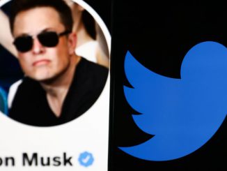 Twitter logo displayed on a phone screen and Elon Musk's Twitter account displayed on a screen in the background are seen in this illustration photo taken in Poland on April 24, 2022. JAKUB PORZYCKI/BENZINGA