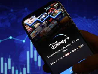 In this photo illustration, logo of Disney+ is displayed on mobile phone screen in front stock exchange screen, in Ankara, Turkiye on May 18, 2023. HAKAN NURAL/BENZINGA