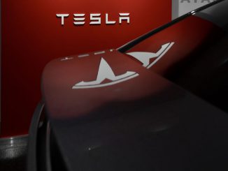 Photo of the Tesla logo behind a car. Third party wrap configurator Wrapmate rolls out wrap choices in various colors and textures for Tesla Cybertruck. MILAN CSIZMADIA/UNSPLASH.