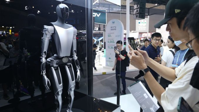 Visitors view the Tesla Bot humanoid robot of Tesla Optimus at the 2023 World Artificial Intelligence Conference in Shanghai, China, July 6, 2023. Tesla CEO strongElon Musk has /strongsaid the first Optimus bot that will have all the Tesla-designed actuators integrated and walking will be ready by around November. (CFOTO/Future Publishing via Getty Images)