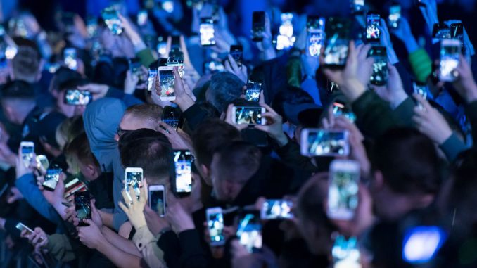 Spectators hold up mobile phones at an event on May 2, 2018 in Cardiff, United Kingdom. (MATTHEW HORWOOD/GETTY)