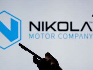  Nikola Corporation logo is seen in the background of a silhouetted woman holding a mobile phone. The amendment will change the required votes from a majority of the outstanding common stock to a majority of the shares actually voting on the proposal. RAFAEL HENRIQUE/SOPA IMAGES/LIGHTROCKET VIA GETTY IMAGES.